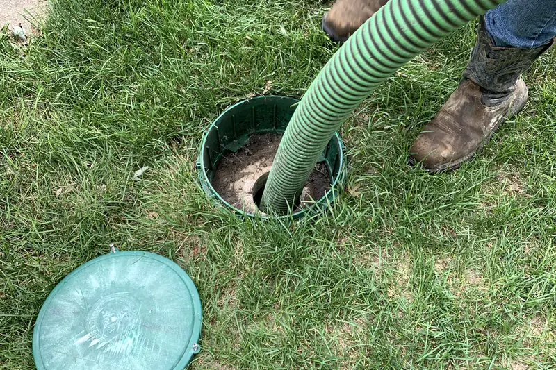 Crew boots and green hose at a septic riser